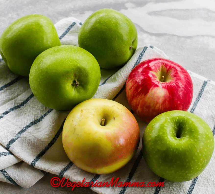 Apples of various color atop white and black stripe cloth