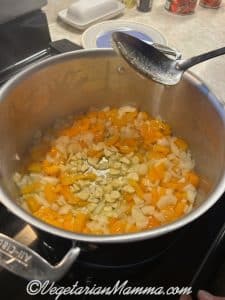 With your large spoon or spatula, sweep out a clear circle in the center of your veggies and add the garlic.