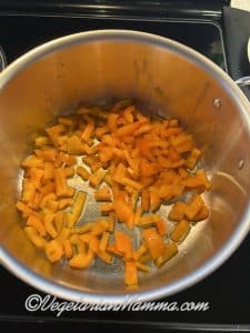 In a large stockpot, orange bell peppers are sautéing.