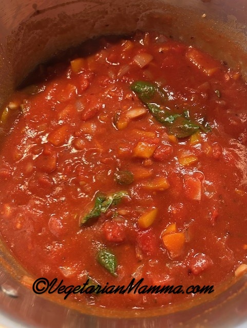In a large stock pot, a tomato sauce with fresh basil and oregano.