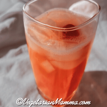 A tall rocks glass filled with yummy Tarte and Dirty drink and a cherry.