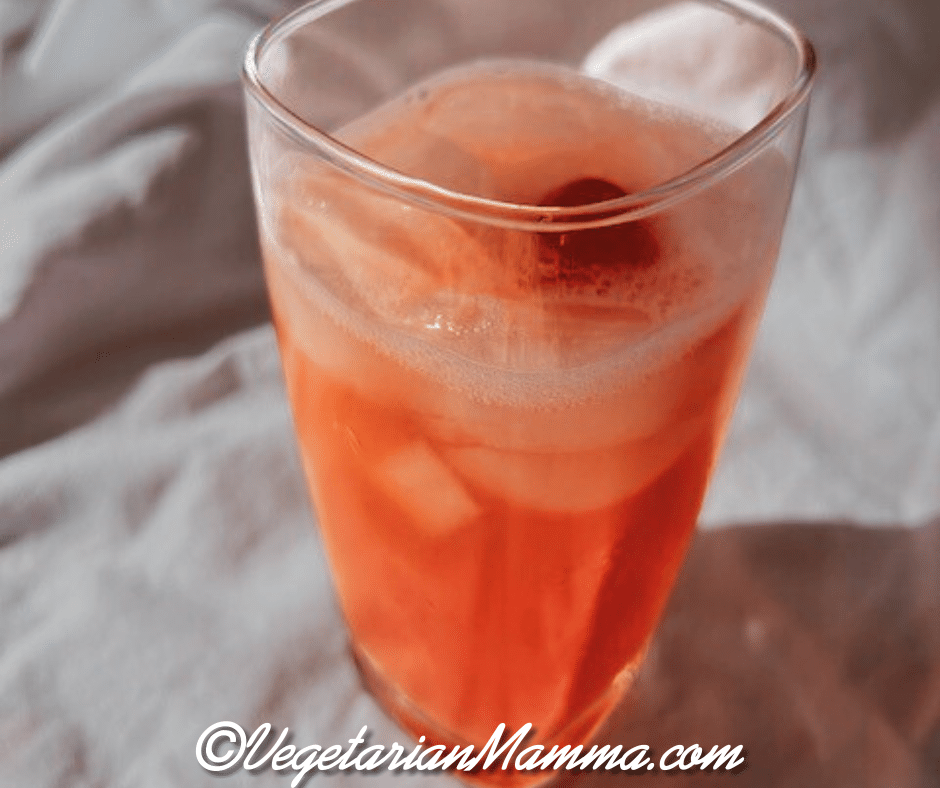 A tall rocks glass filled with yummy Tarte and Dirty drink and a cherry.