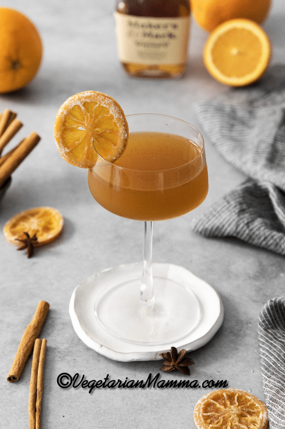 Winter Orange Whiskey Cocktail in a stem glass with a dried orange for garnish on a white coaster.