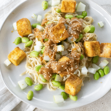 Overhead of a tofu noodle bowl on a round white plate
