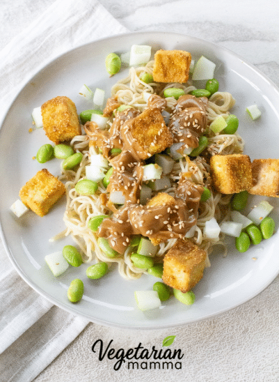 Overhead of a tofu noodle bowl on a round white plate